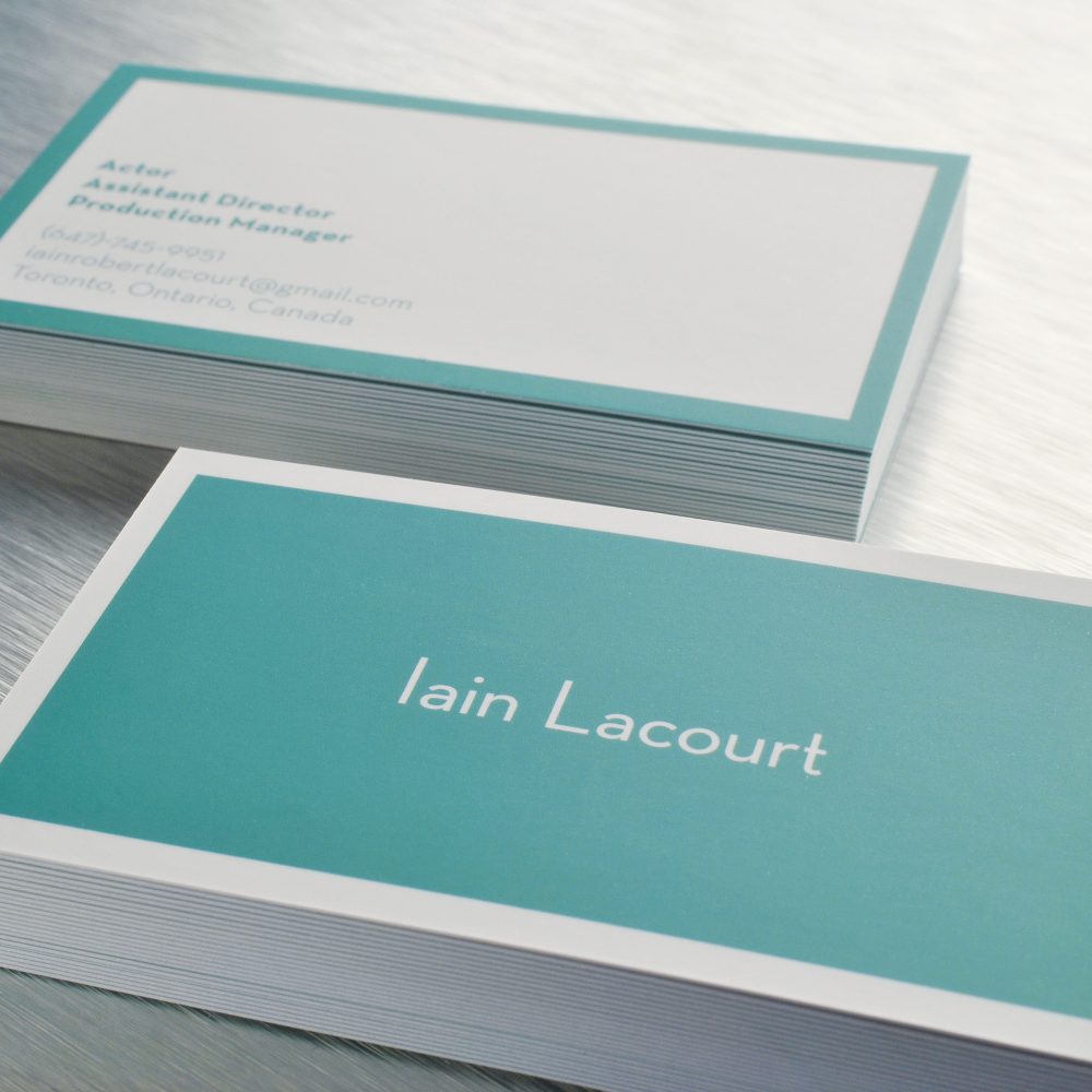 Stacks of teal and white silk-laminated business cards showing the printed face and layered edges.