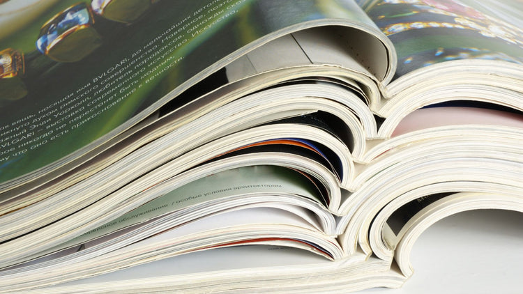Stack of open glossy booklets and magazines showing curved bound pages