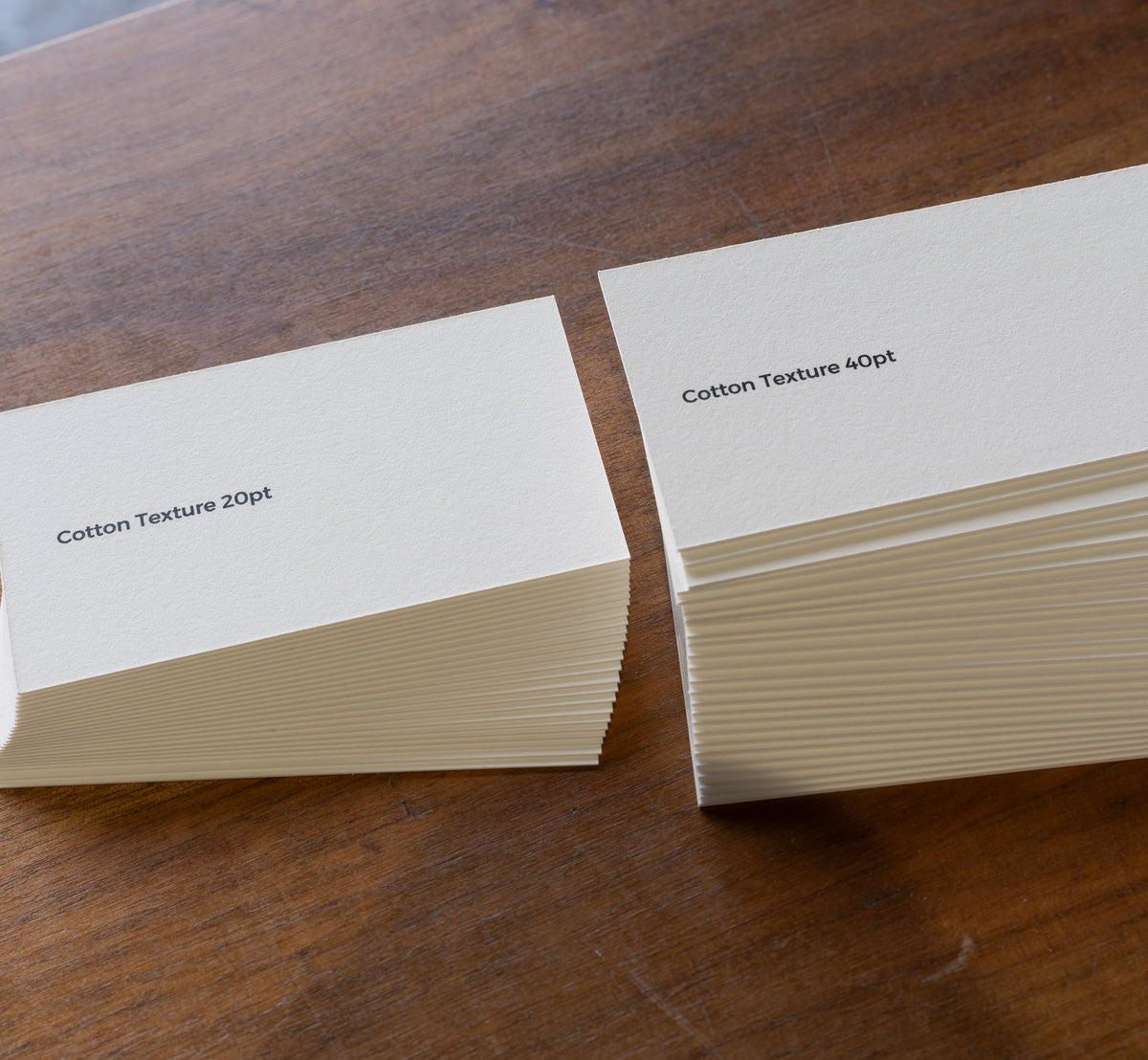 Stacks of warm-white cotton-textured business card stock in 20 pt and 40 pt weights.