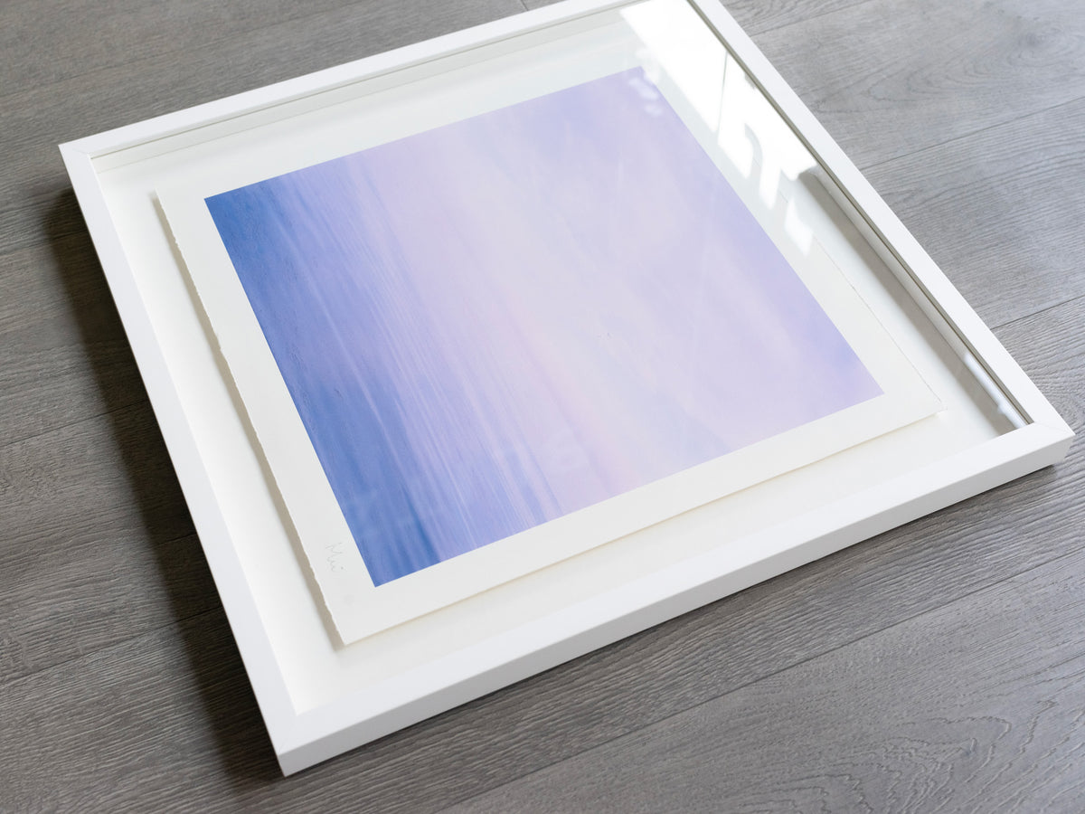 White shadow box frame containing a blue print with deckled paper edges.