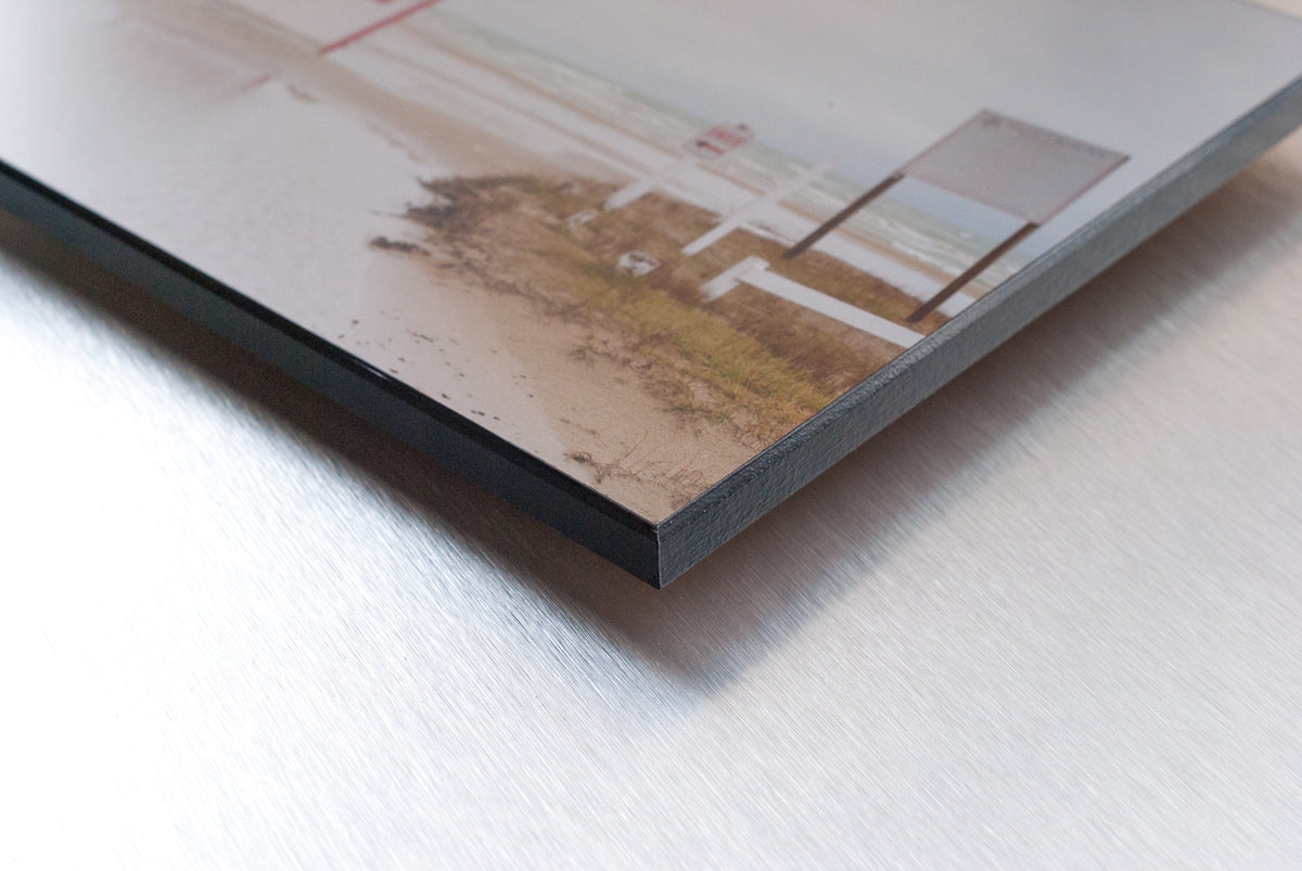 Close-up of a plaque-mounted beach photograph showing the black edge and front corner.