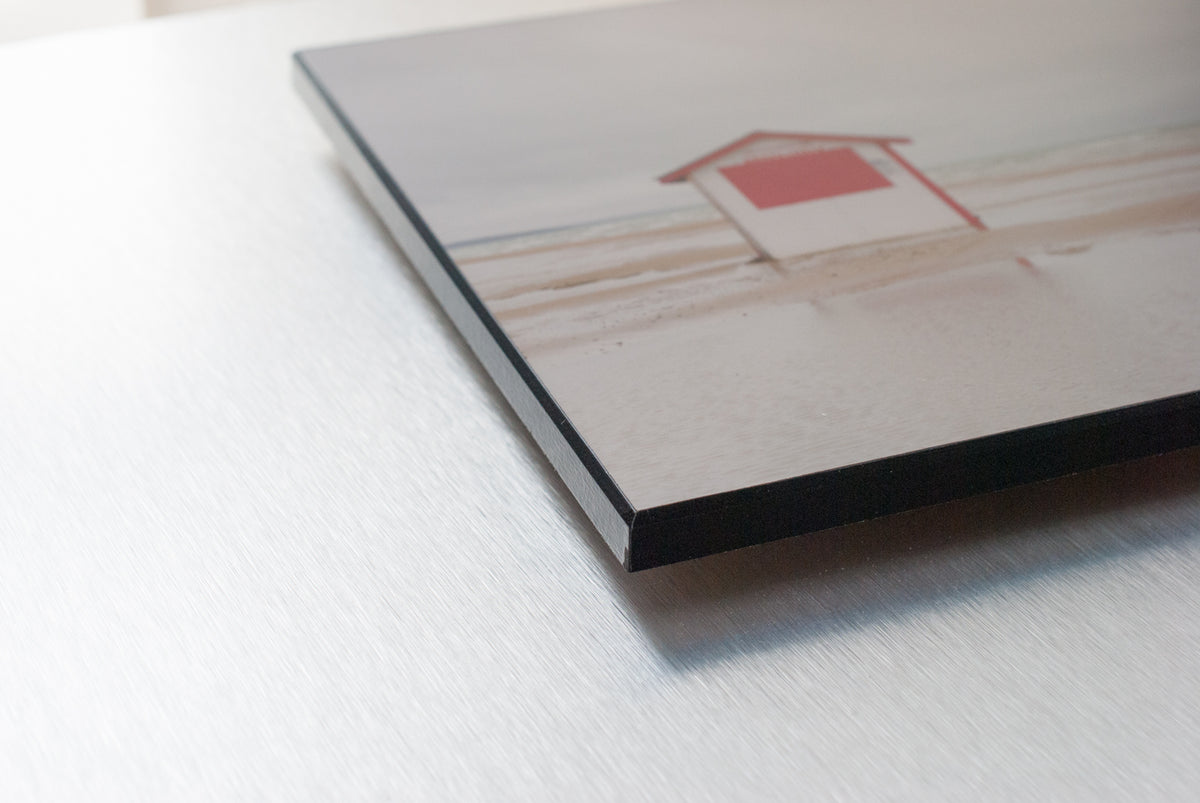 Angled close-up of a plaque-mounted beach photograph showing the black edge.