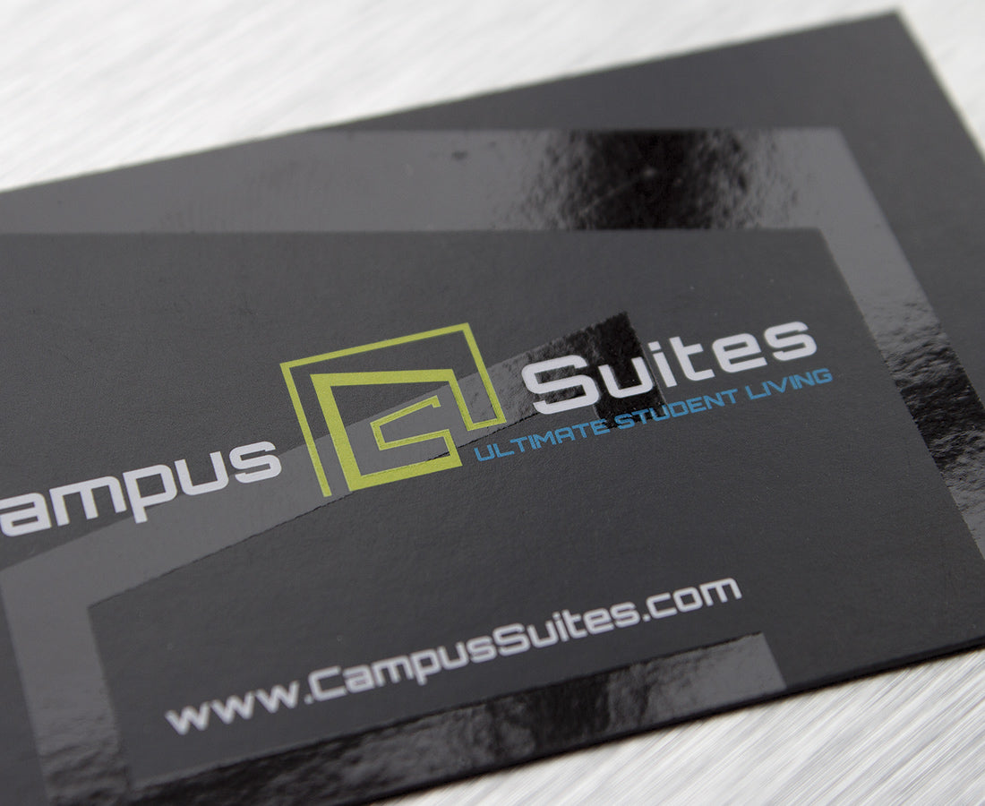 Black business cards with glossy raised bands and logo details on a matte surface.